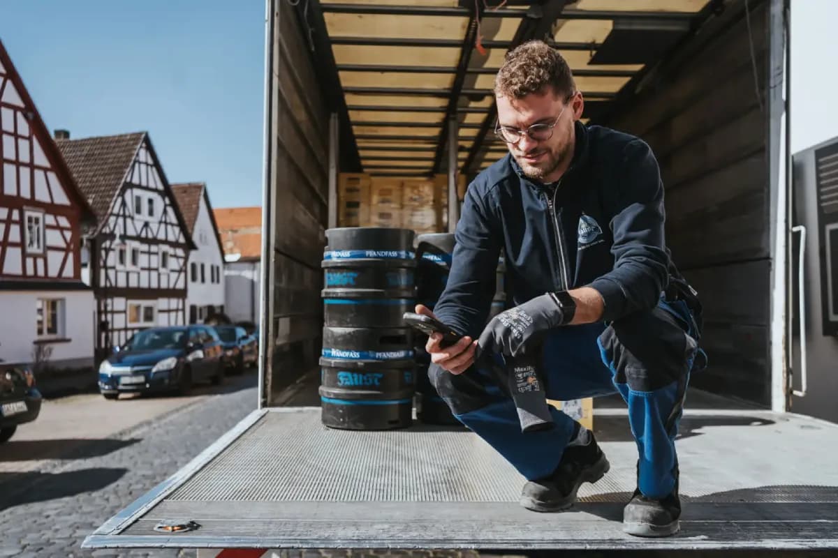 A delivery driver using a handheld device at the tailgate of a loaded truck