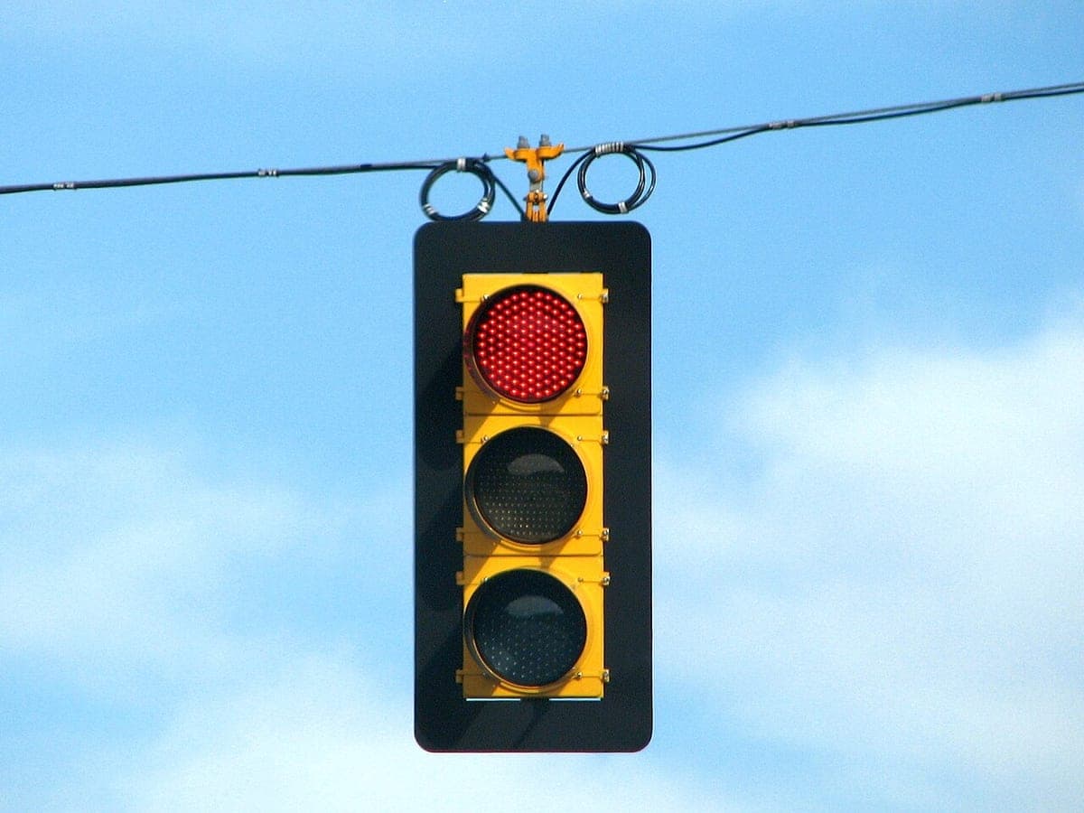 Lampu lalu lintas LED merah tergantung dengan latar langit biru